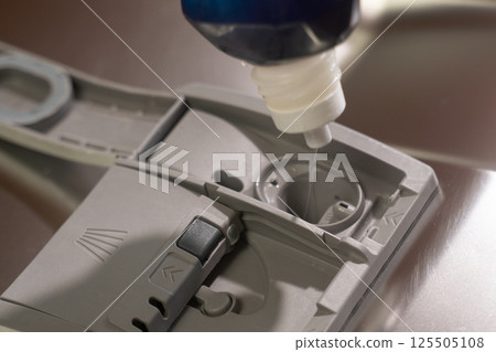 Housekeeper pouring detergent into dishwasher compartment 125505108