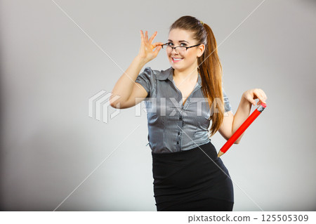 Teacher looking elegant woman holding big pencil Teacher looking elegant woman holding big pencil 125505309