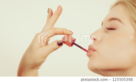 Woman applying lipstick or lip gloss 125505398