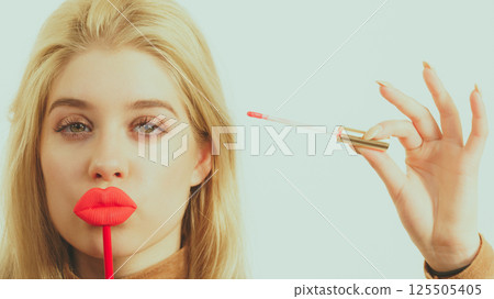 Woman applying lipstick or lip gloss Woman applying lipstick or lip gloss 125505405