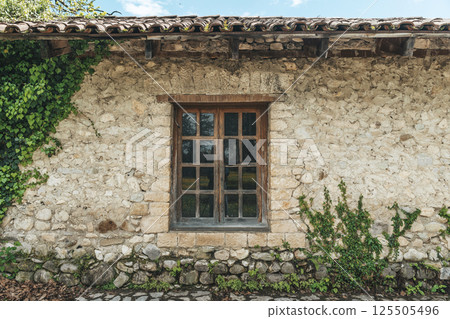 Old European village stone house with windows and tiled roof 125505496