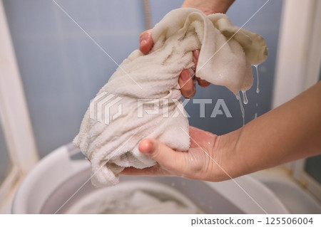 A Person Actively Washing Clothes While Using a Modern Washing Machine for Laundry Tasks 125506004