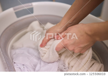A Person Actively Washing Clothes While Using a Modern Washing Machine for Laundry Tasks A Person Actively Washing Clothes While Using a Modern Washing Machine for Laundry Tasks 125506010