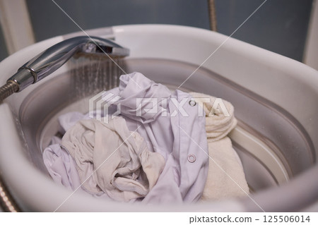 A Person Actively Washing Clothes While Using a Modern Washing Machine for Laundry Tasks A Person Actively Washing Clothes While Using a Modern Washing Machine for Laundry Tasks 125506014