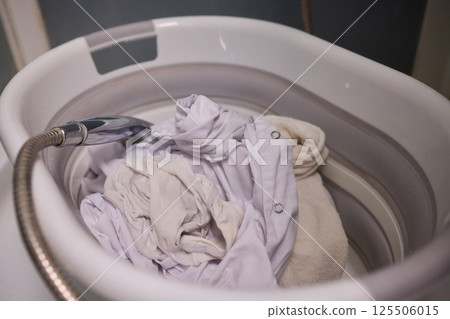 A Person Actively Washing Clothes While Using a Modern Washing Machine for Laundry Tasks A Person Actively Washing Clothes While Using a Modern Washing Machine for Laundry Tasks 125506015