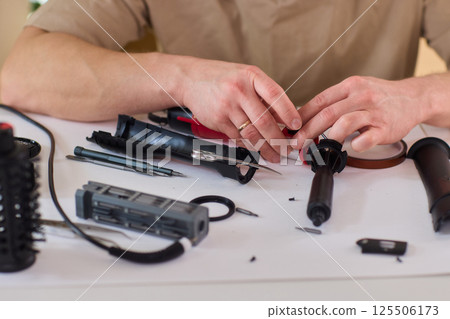 Hands of skilled workers diligently engaged in the intricate repair of mechanical devices Hands of skilled workers diligently engaged in the intricate repair of mechanical devices 125506173