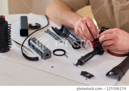 Hands of skilled workers diligently engaged in the intricate repair of mechanical devices 125506174