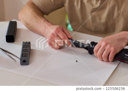 Hands of skilled workers diligently engaged in the intricate repair of mechanical devices Hands of skilled workers diligently engaged in the intricate repair of mechanical devices 125506236