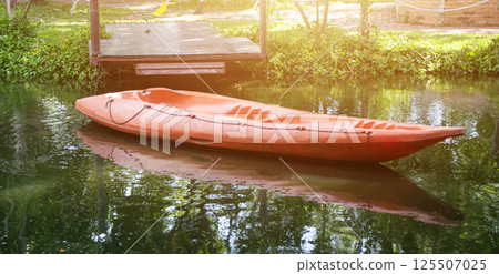 An orange kayak is parked at a dock on the lake. An orange kayak is parked at a dock on the lake. 125507025