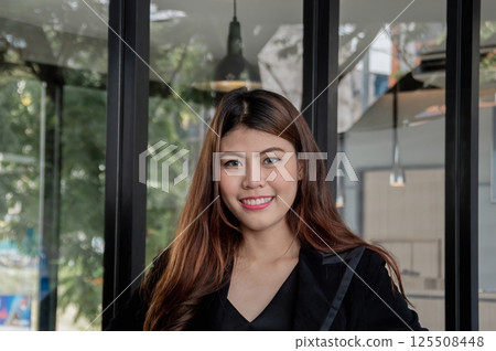A cheerful young woman smiles confidently in a modern workspace, exuding positivity and professionalism. A cheerful young woman smiles confidently in a modern workspace, exuding positivity and professionalism. 125508448