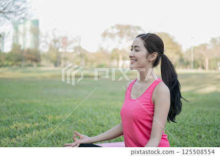 A young woman practices yoga in a peaceful park, surrounded by nature, embodying calmness and mindfulness. A young woman practices yoga in a peaceful park, surrounded by nature, embodying calmness and mindfulness. 125508554