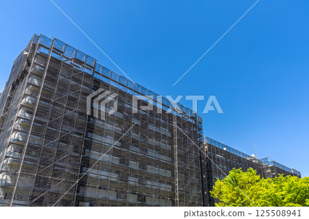 Yokohama cityscape in Japan. Apartment building repairs and inspections, scaffolding and protective nets. Satellite antennas outside the nets... 125508941