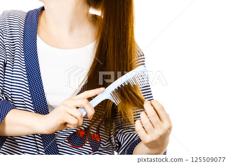 Woman brushing her long hair using comb Woman brushing her long hair using comb 125509077