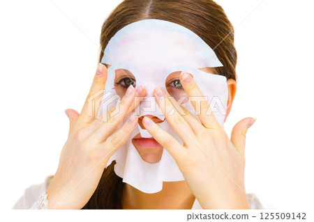 Woman applying sheet mask on face 125509142