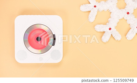 White portable CD player on a beige background with a decorative snowflake 125509749