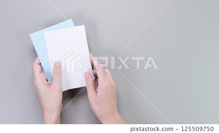 Slender Female Hands Holding Blank Note Cards On A Solid Gray Background 125509750