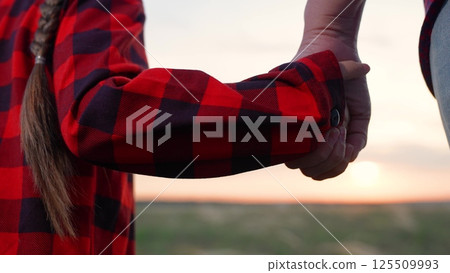 Daughter parent holding hands in field. Girl kid child woman mother mom join palms arms hands while standing in meadow grassland. Strength trust hope rely happy family emotional support strong bond. Daughter parent holding hands in field. Girl kid child woman mother mom join palms arms hands while standing in meadow grassland. Strength trust hope rely happy family emotional support strong bond. 125509993