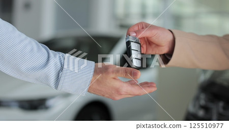 Young man buying a car from a dealer. Car seller hands over the keys to the buyer. Auto business concept. Young man buying a car from a dealer. Car seller hands over the keys to the buyer. Auto business concept. 125510977