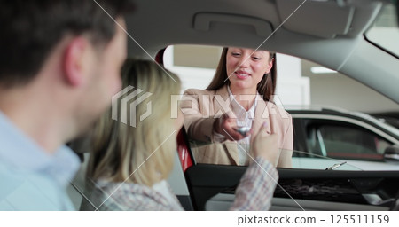 Woman agent saleswoman manager give keys to new car happy couple family buyers clients sit inside auto choosing buying automobile dealership. Woman agent saleswoman manager give keys to new car happy couple family buyers clients sit inside auto choosing buying automobile dealership. 125511159
