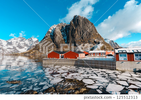 Red Cabins by Frozen Lake and Mountain at Hamnoy village, Lofoten. Red Cabins by Frozen Lake and Mountain at Hamnoy village, Lofoten. 125512313