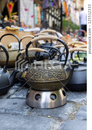 Traditional asian teapots displayed on metal stand in outdoor market Traditional asian teapots displayed on metal stand in outdoor market 125512333