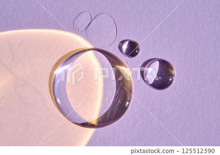 A drop of serum or micellar water on a purple background. 125512390