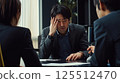 Stressed businessman sits at meeting table du difficult business negotiation. 125512470