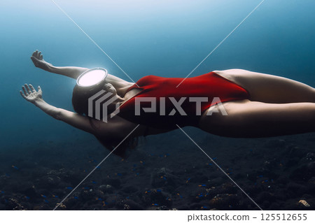 Gorgeous woman freediver in red swimwear swims underwater in deep ocean. Sexy woman freediving. 125512655