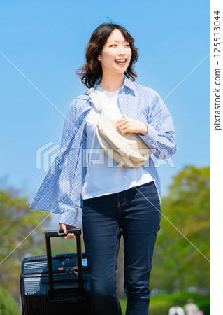 A woman traveling with a suitcase 125513044