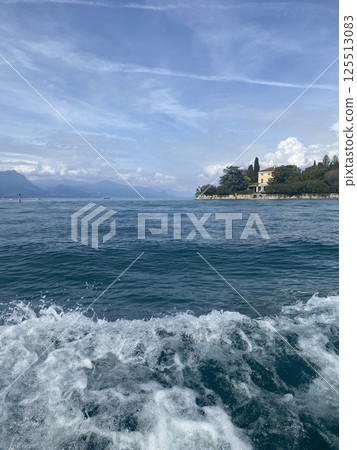 Scenic view of Garda lake with buildings and mountains on the background, Italy 125513083