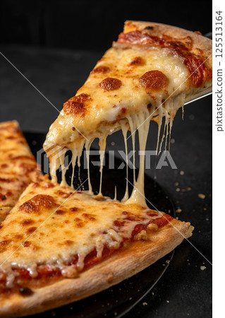 Pizza slice with stretchy melted cheese being lifted, fresh and hot with crispy crust 125513164