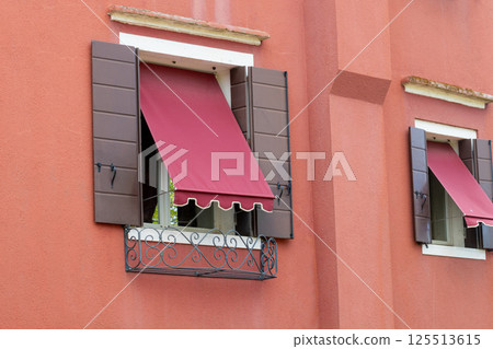 Red House with Brown Shutters and Red Awnings 125513615