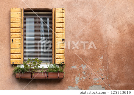 Rustic window with wooden shutters and flower box on weathered wall Rustic window with wooden shutters and flower box on weathered wall 125513619