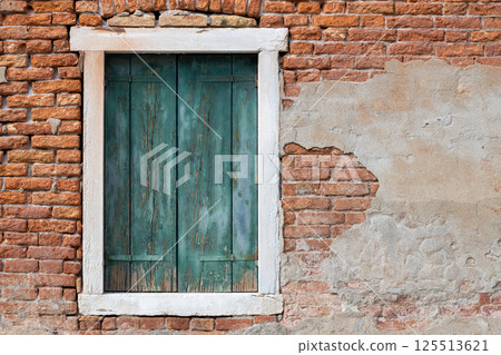 Aged green window shutters on rustic brick wall with peeling plaster 125513621