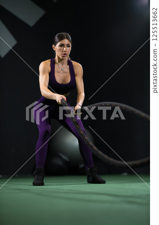 dedicated athlete performs high intensity workout using battle ropes in modern fitness studio. environment is equipped various exercise tools promoting active lifestyle. dedicated athlete performs high intensity workout using battle ropes in modern fitness studio. environment is equipped various exercise tools promoting active lifestyle. 125513662