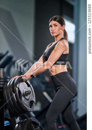 determined individual works out in modern gym engaging heavy weights. environment showcases fitness equipment and bright lighting emphasizing dedication and strength. determined individual works out in modern gym engaging heavy weights. environment showcases fitness equipment and bright lighting emphasizing dedication and strength. 125513689
