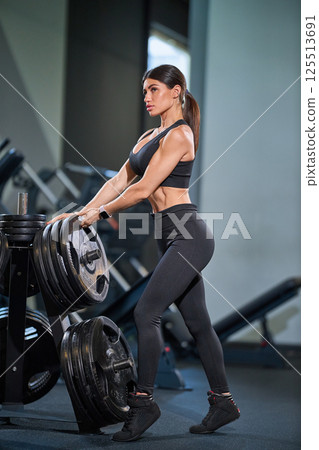 fitness enthusiast lifts heavy barbell weights in contemporary gym focused on strength training. workout emphasizes physical fitness and determination showcasing dedication exercise. 125513691