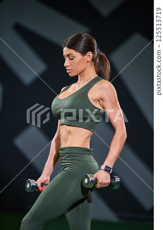 Focused individual performs strength training session holding dumbbells in sleek gym environment showcasing dedication fitness and wellness. Focused individual performs strength training session holding dumbbells in sleek gym environment showcasing dedication fitness and wellness. 125513719