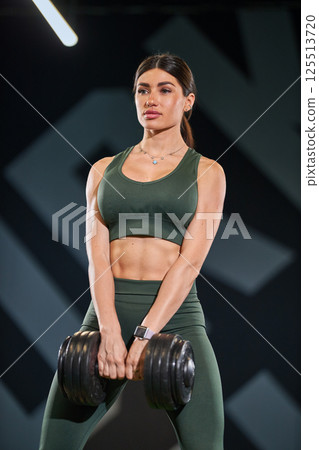 athletic individual exercises heavy dumbbell in contemporary gym. athletic individual exercises heavy dumbbell in contemporary gym. 125513720