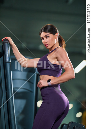 fitness enthusiast showcases her strong physique while standing next gym equipment in contemporary fitness center. atmosphere is energetic and motivating. fitness enthusiast showcases her strong physique while standing next gym equipment in contemporary fitness center. atmosphere is energetic and motivating. 125513730
