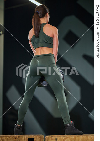 Woman in athletic wear engaged in deadlift exercises within contemporary gym environment focusing on strength training and physical fitness. Woman in athletic wear engaged in deadlift exercises within contemporary gym environment focusing on strength training and physical fitness. 125513742