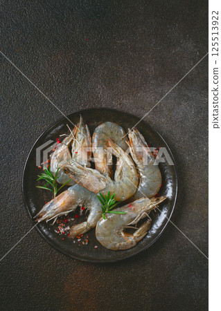 Fresh raw white-footed shrimp, tiger prawns vannamei, on a black plate, with spices and herbs, 125513922