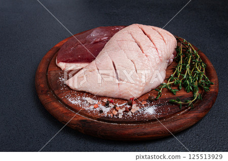 Fresh raw duck breasts, on a wooden chopping board, with herbs and spices, no people 125513929