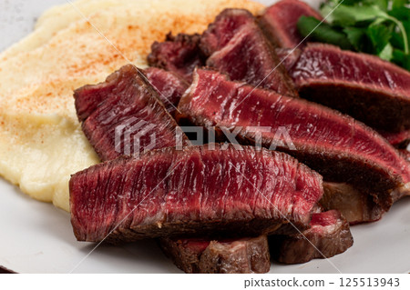 Sliced steak, served with creamy mashed potatoes, and fresh herbs, no people 125513943