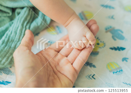 Father's hand gently holding his baby's tiny foot, symbolizing love, protection, and family bond. Parenthood, care, and tenderness concept Father's hand gently holding his baby's tiny foot, symbolizing love, protection, and family bond. Parenthood, care, and tenderness concept 125513955