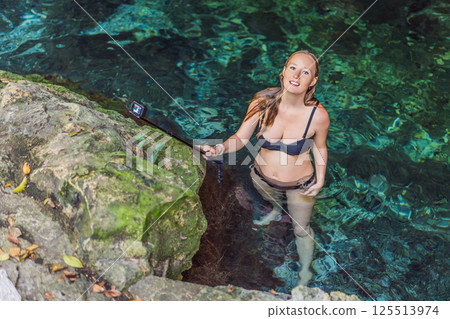 Female tourist enjoying a refreshing swim in a Mexican cenote with turquoise water. Adventure, travel, and nature exploration concept Female tourist enjoying a refreshing swim in a Mexican cenote with turquoise water. Adventure, travel, and nature exploration concept 125513974