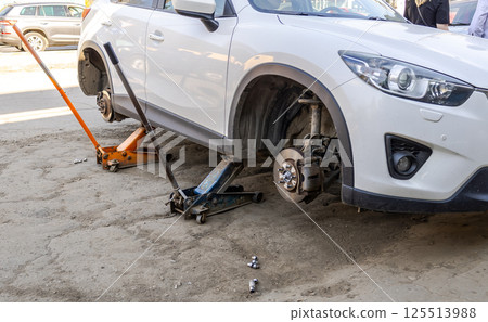 Car without wheels and lift up by jack stand .Waiting for tire replacement Car without wheels and lift up by jack stand .Waiting for tire replacement 125513988