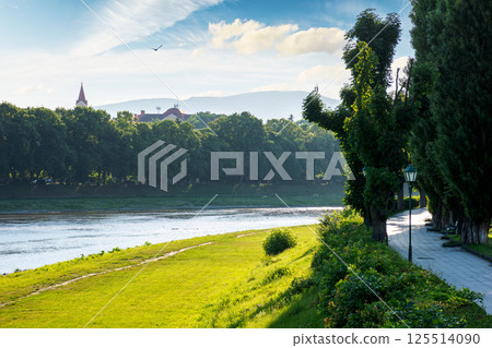 embankment of the river uzh in morning light. historic center of uzhhorod city. wonderful urban landscape in summer. linden alley on the left shore 125514090