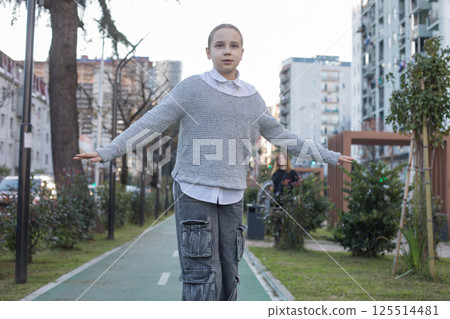 Cheerful young girl child in casual with skateboard outdoors 125514481