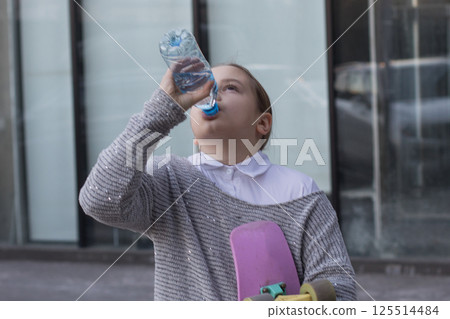 Cute child girl drinking water from a bottle outdoors 125514484